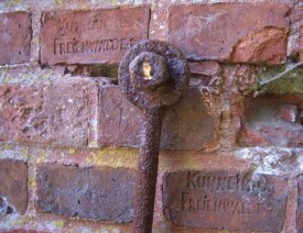 Detailaufnahme der Mauer... - ... am  Haupttor. Zu sehen ist ein Teil eines eisernen Hakens und die eingebrannten Namen der Ziegelei in Bad Freienwald, die einen Teil Ziegel für die Lünette hergestellt hat.