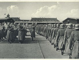 Parade im Lager mit Blasmusik - Auf einem Dach sitzt ein Fotograf.